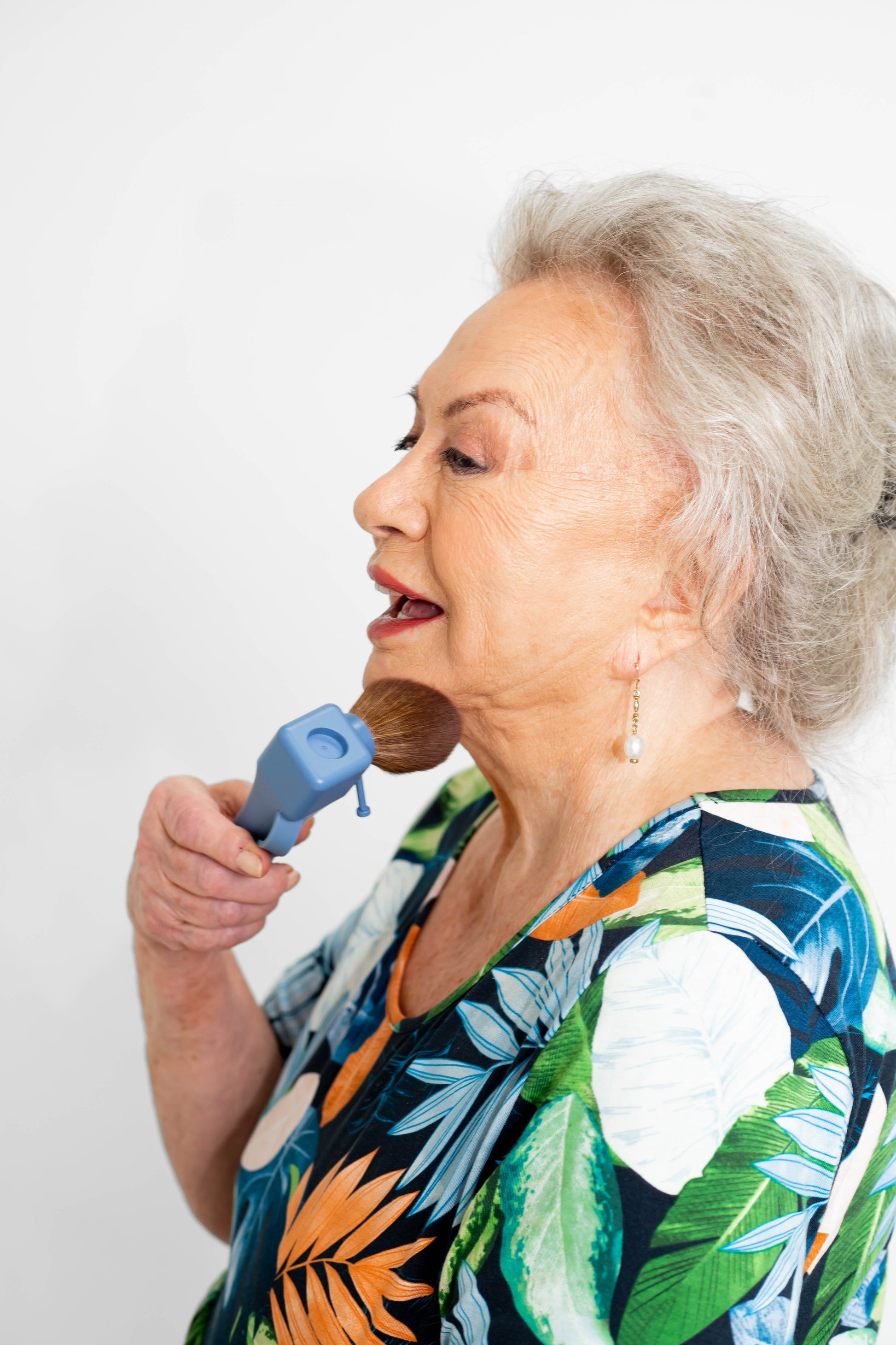 Older mature woman using ergonomic makeup brush for easier grip and better control
